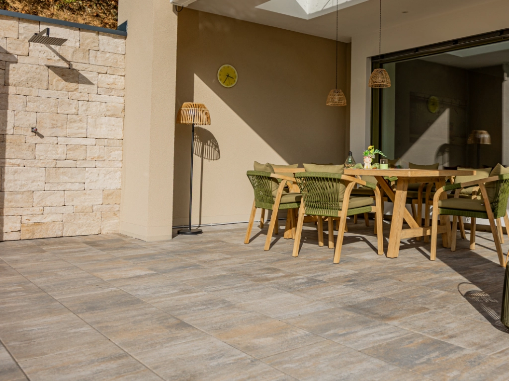 Überdachte Terrasse mit Gartengarnitur, gepflastert mit großformatigem Calido 60 x 40 in Muschelkalk
